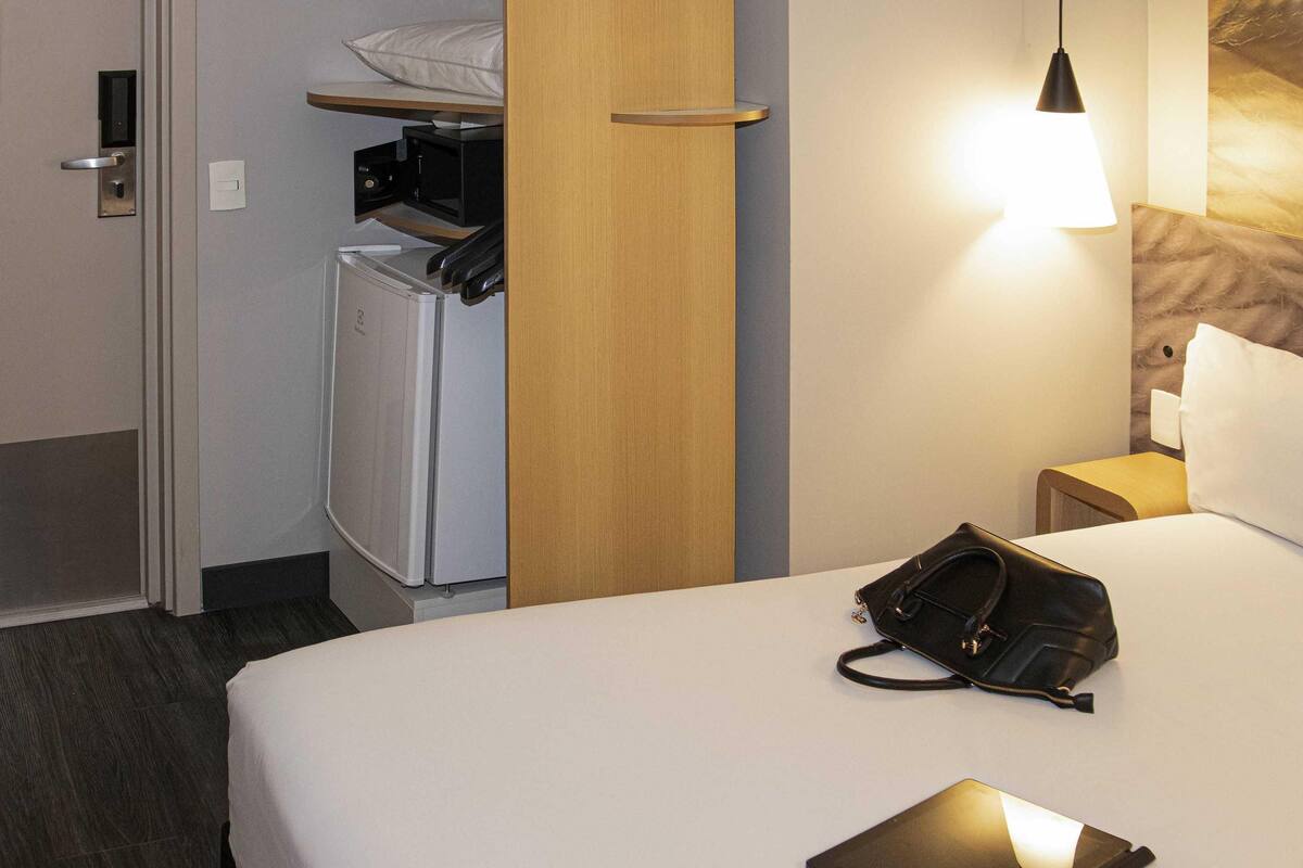 Une chambre d’hôtel équipée d’un lit, d’un bureau, d’une chaise, d’une lampe et d’un réfrigérateur.