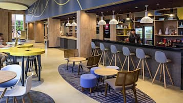 A modern bar area with seating, a counter, and a digital screen.