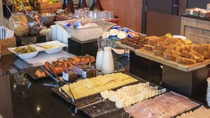 Un bufé con una variedad de alimentos, incluyendo frutas, quesos y pasteles.