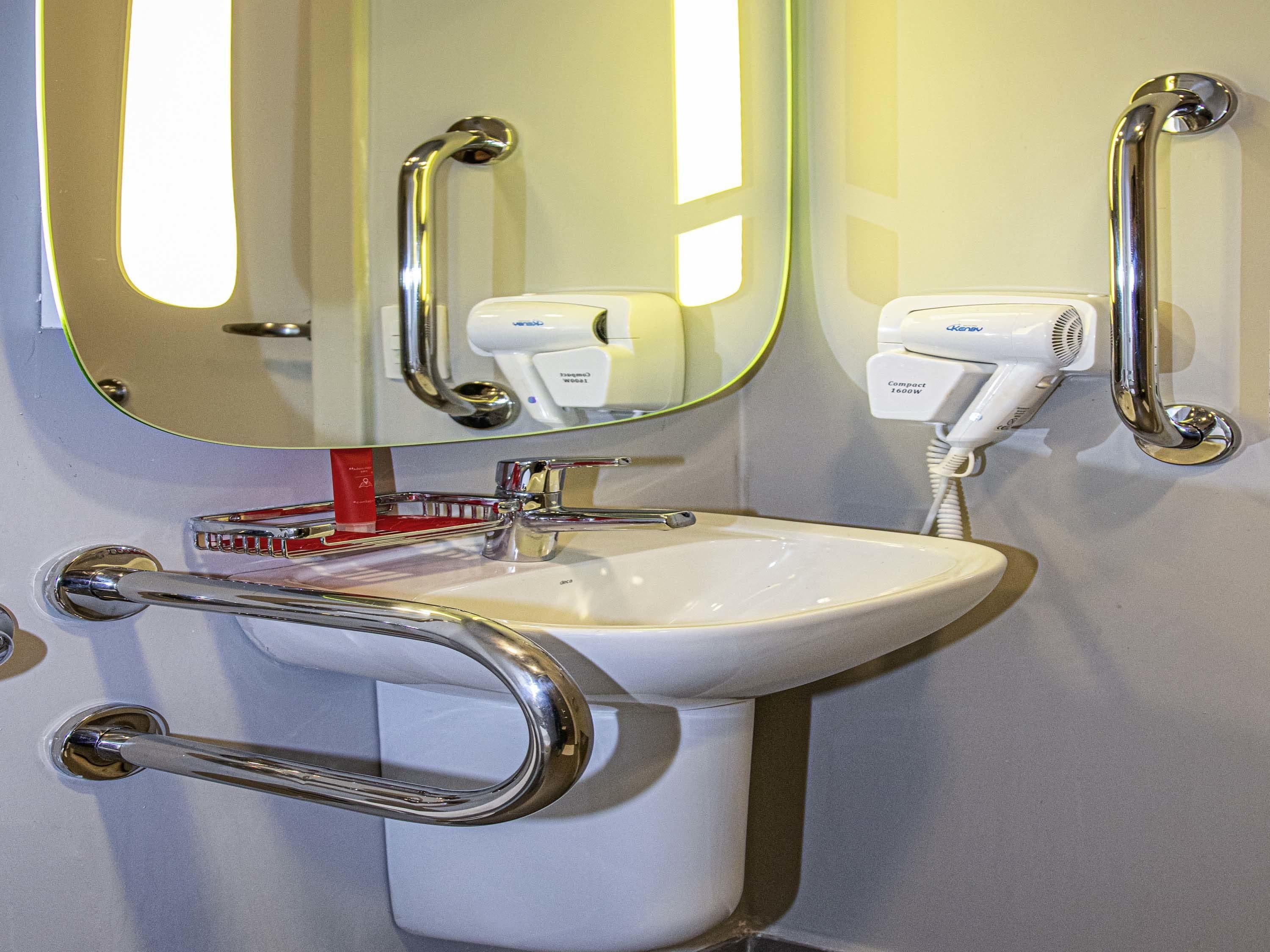 A bathroom with a white sink, chrome fixtures, a mirror, and a hairdryer.