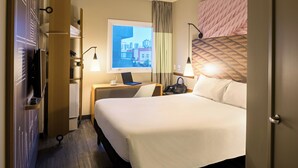 A hotel room with a bed, a desk with a laptop, a window with a city view, and a wardrobe. - ibis Sao Paulo Tatuape (São Paulo)
