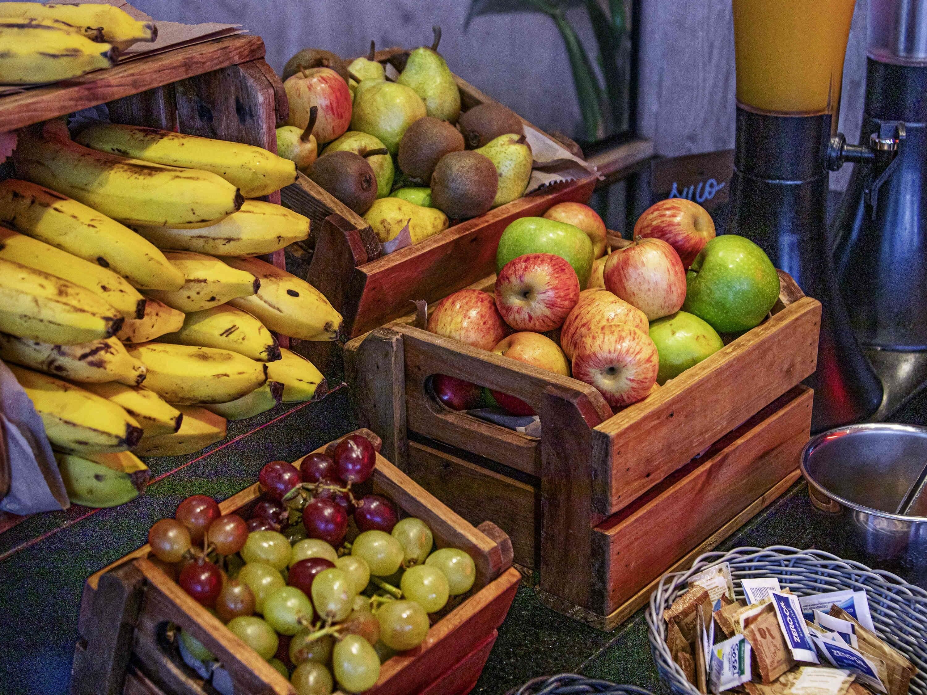 Wooden crates filled with bananas, apples, pears, and grapes.
