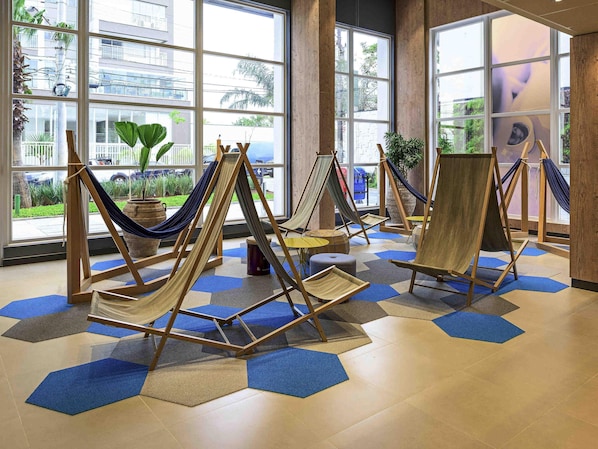 A room with large windows, hammocks, and a view of the outside.