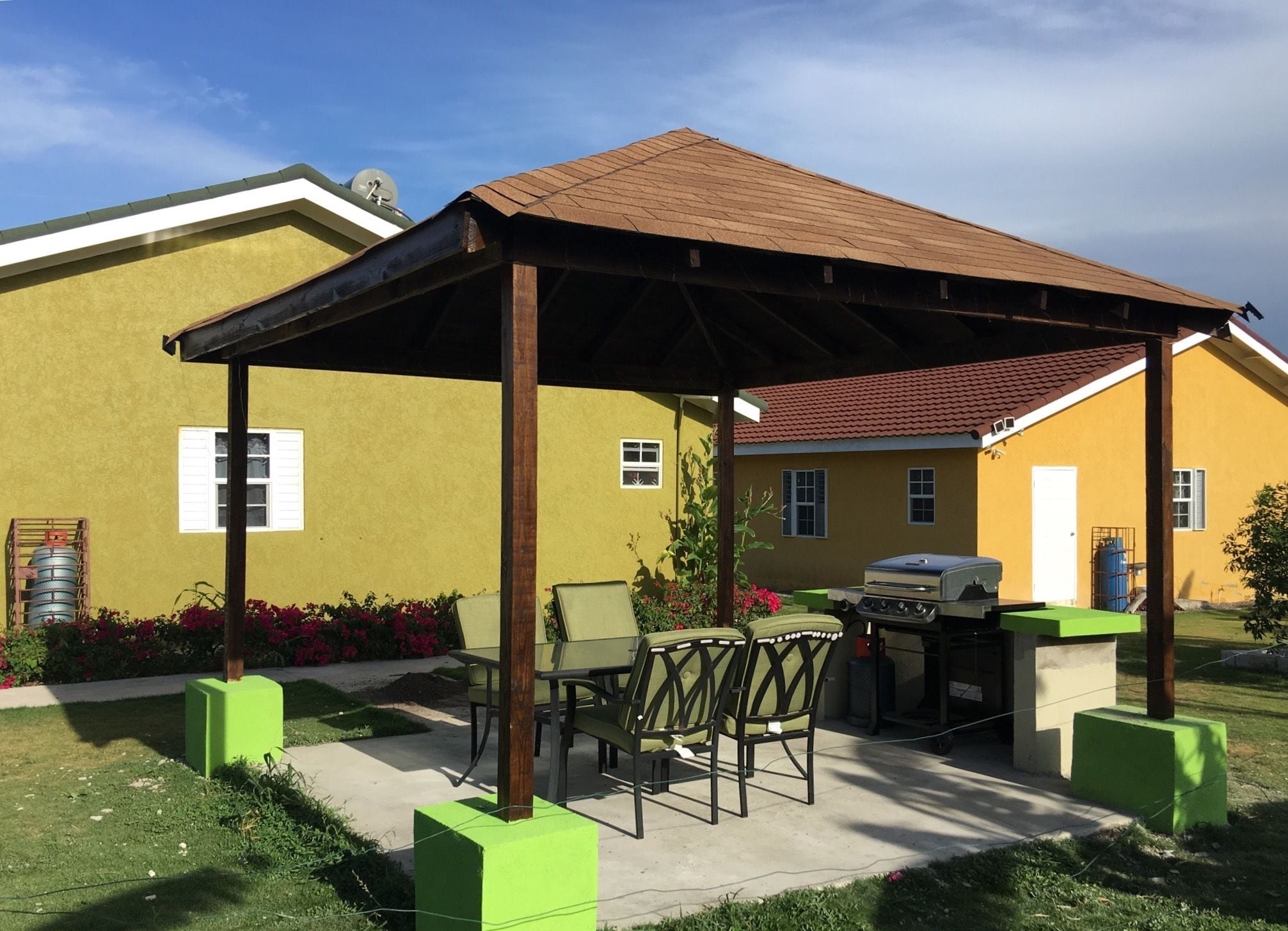 A covered patio area with outdoor furniture, a grill, and a water tank.