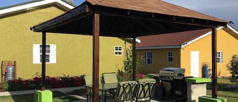 A covered patio area with outdoor furniture, a grill, and a water tank.