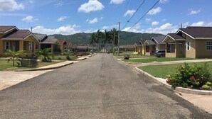 A residential street with houses, a clear sky, and mountains in the background. - Drax Hall Country Club's Sweet Escape (Ocho Rios)