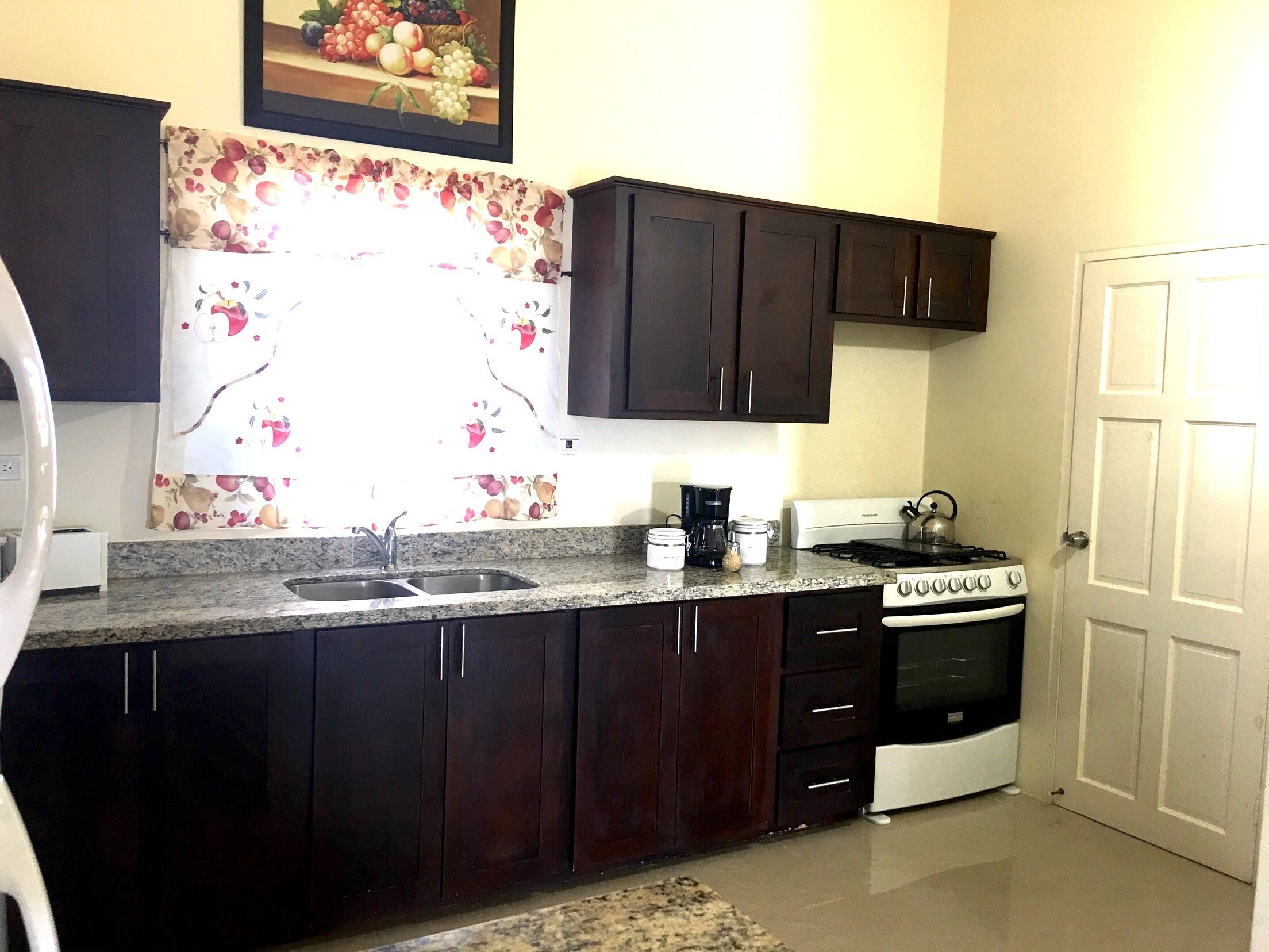 A kitchen with dark wooden cabinets, a granite countertop, a stove, and a sink.