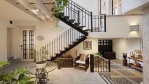 A spacious interior with a central staircase, a seating area with a sofa and armchairs, and a dining table with potted plants. - H21 Hospedaje Boutique (Mexico City)