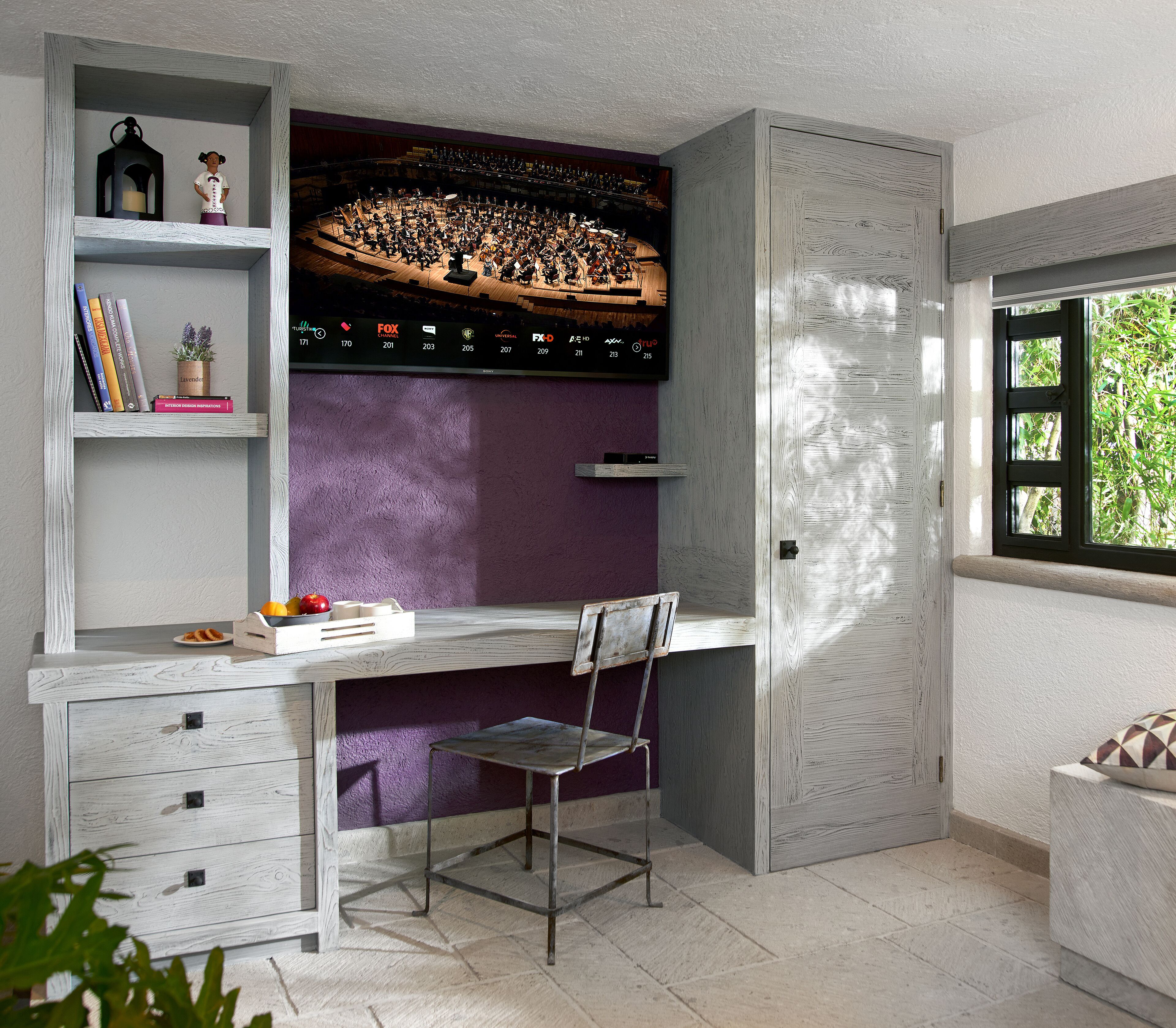 Een kamer met een groot televisiescherm, een bureau, een stoel en een boekenkast.