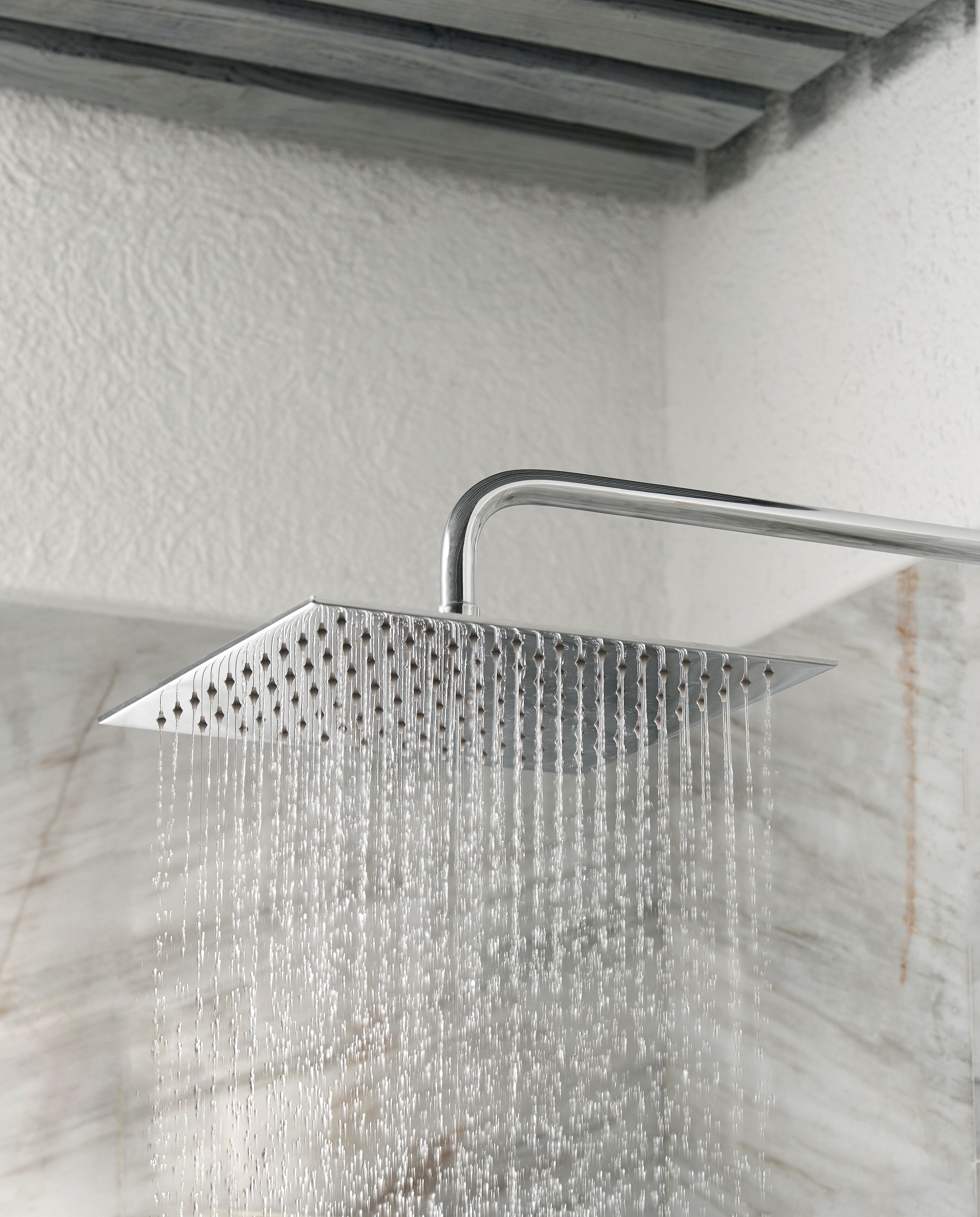 A showerhead with multiple nozzles, water flowing from it, and a marble-like surface below.