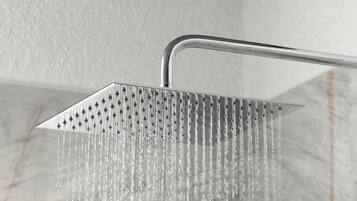 A showerhead with multiple nozzles, water flowing from it, and a marble-like surface below.