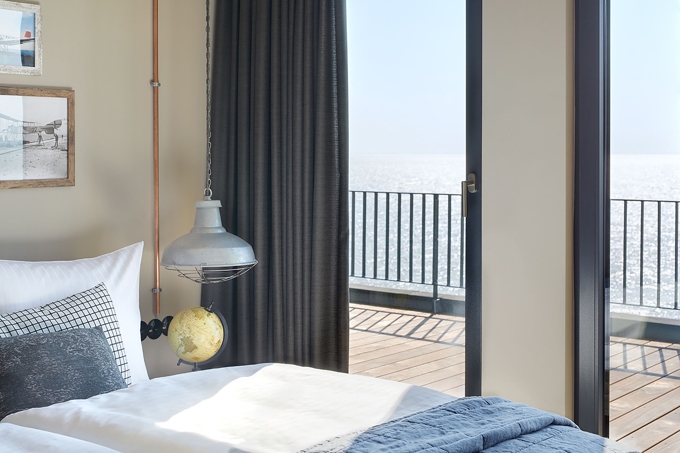 Un dormitorio con cama, un globo terráqueo y vista al mar desde un balcón.
