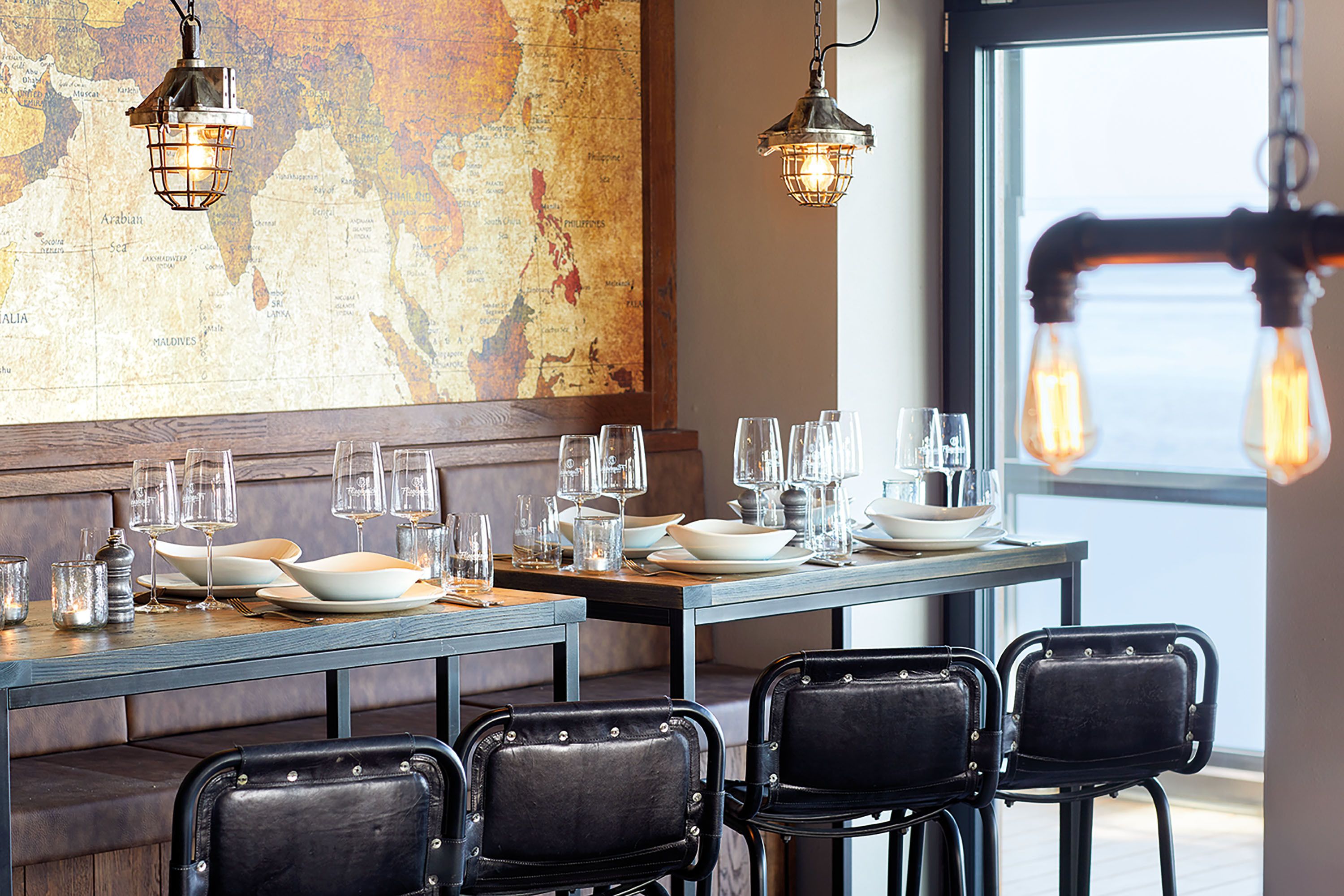 A dining area with a wooden table set for four, equipped with plates, glasses, and cutlery.