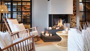 A cozy living room with a fireplace, comfortable seating, and a view of the city. - Lighthouse Hotel & SPA (Büsum)
