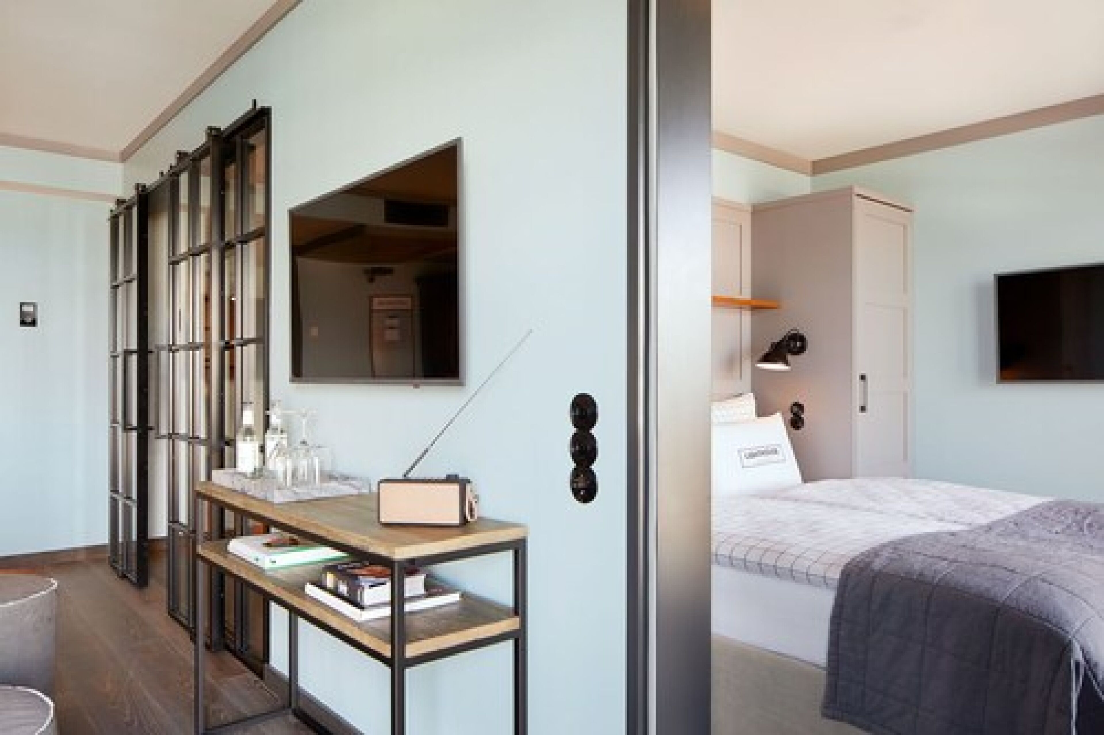 A modern hotel room with a bed, bedside table, and a large mirror.