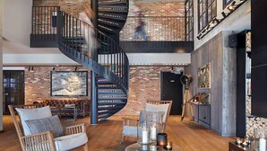 A spacious loft with exposed brick walls, a spiral staircase, and a mix of modern and rustic furniture. - Lighthouse Hotel & SPA (Büsum)