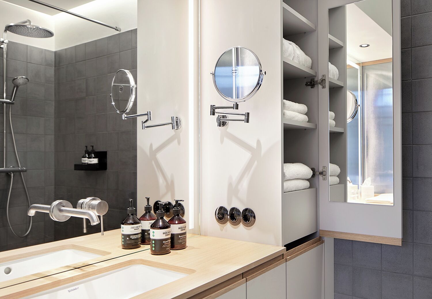 A modern bathroom with a large mirror, a showerhead, and a towel rack.