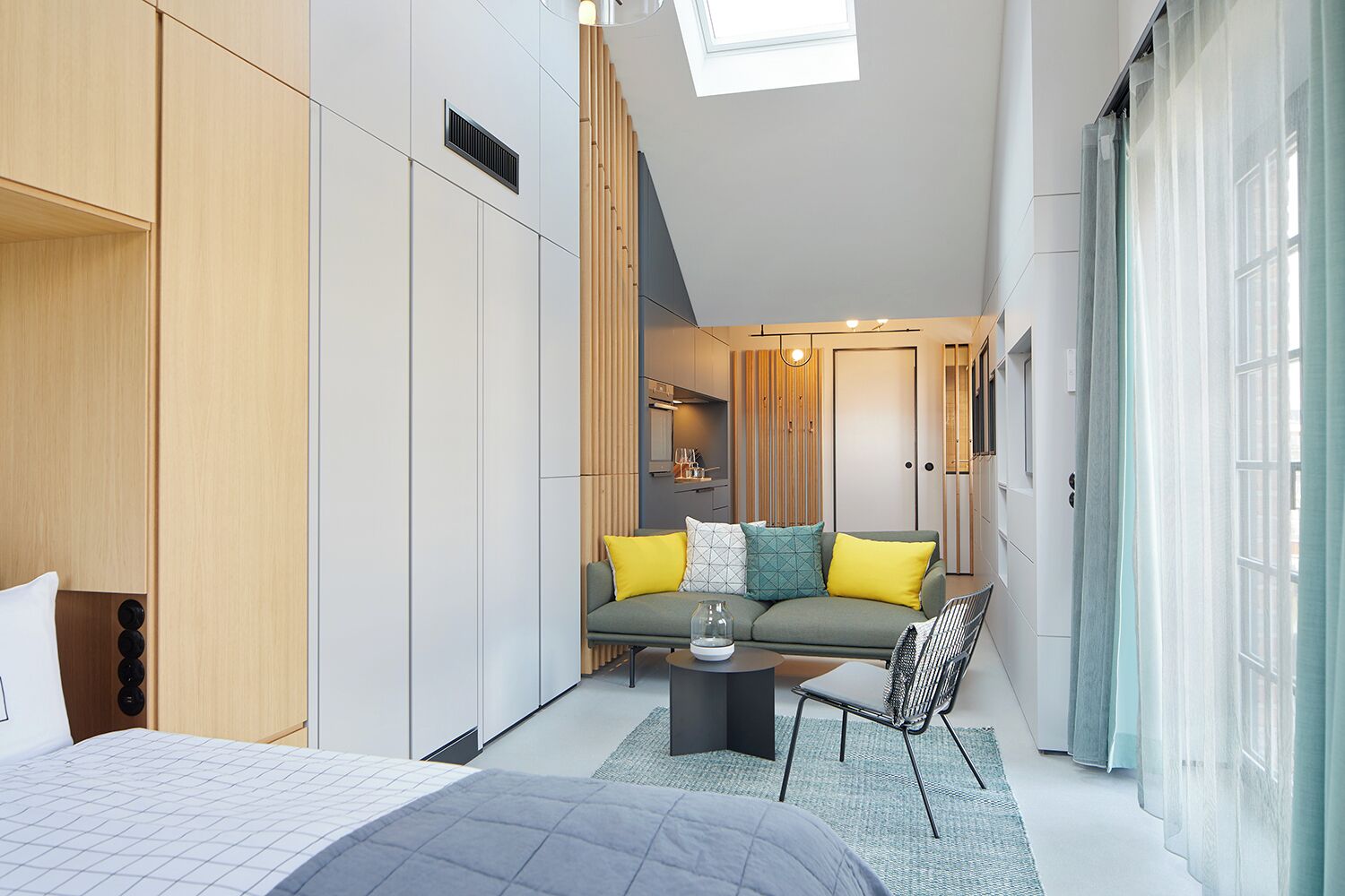 A modern bedroom with a bed, a sofa, and a small table.