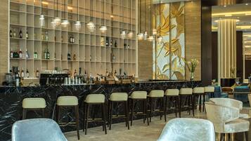 A modern bar area with marble countertops, bar stools, and a decorative wall with shelves.