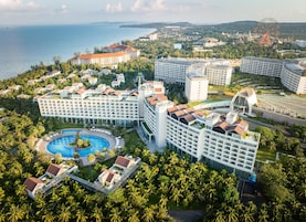 Un resort con varias edificaciones, una piscina grande y vistas al mar.