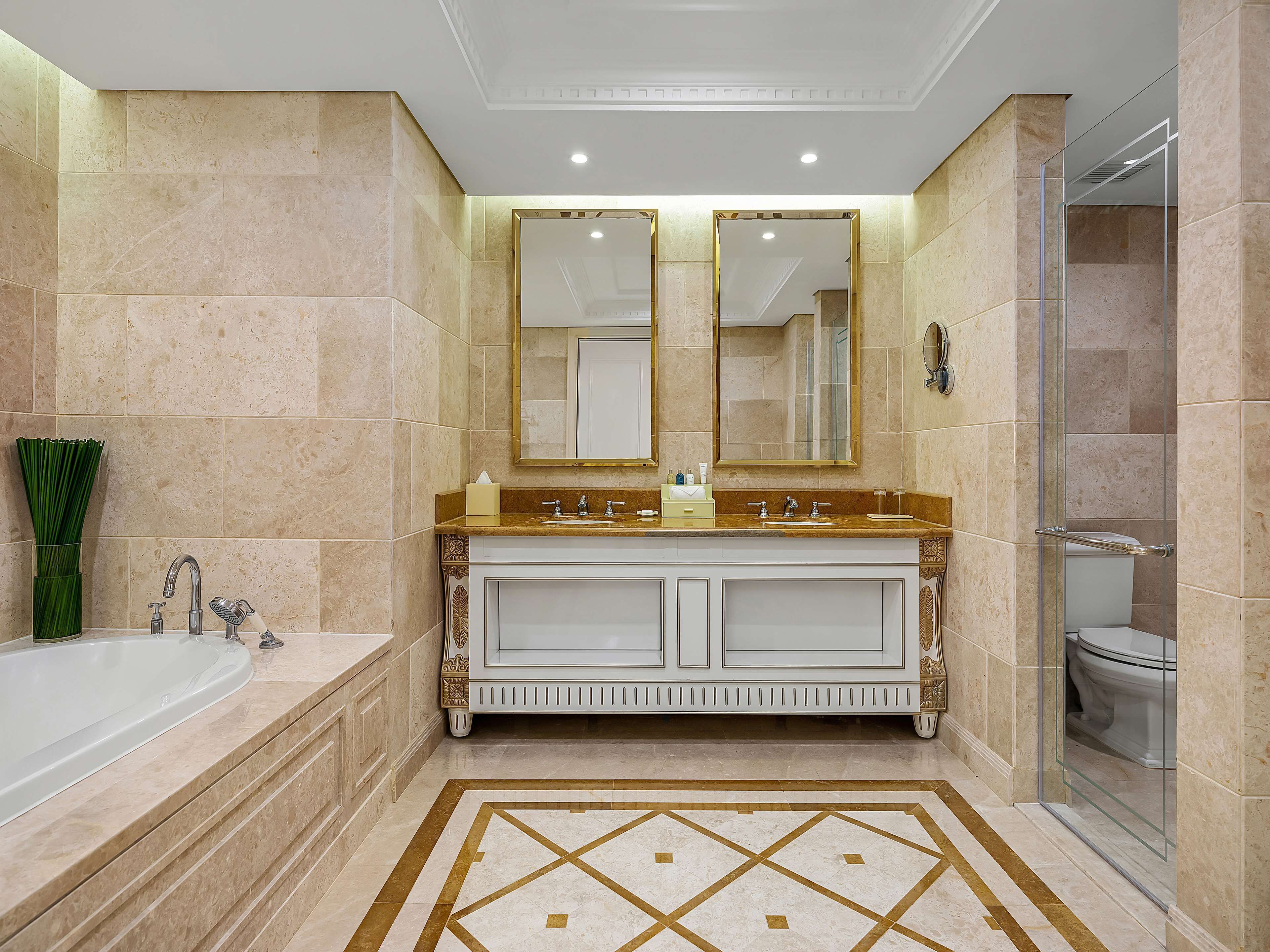 A bathroom with a bathtub, double sinks, a large mirror, and a shower area.
