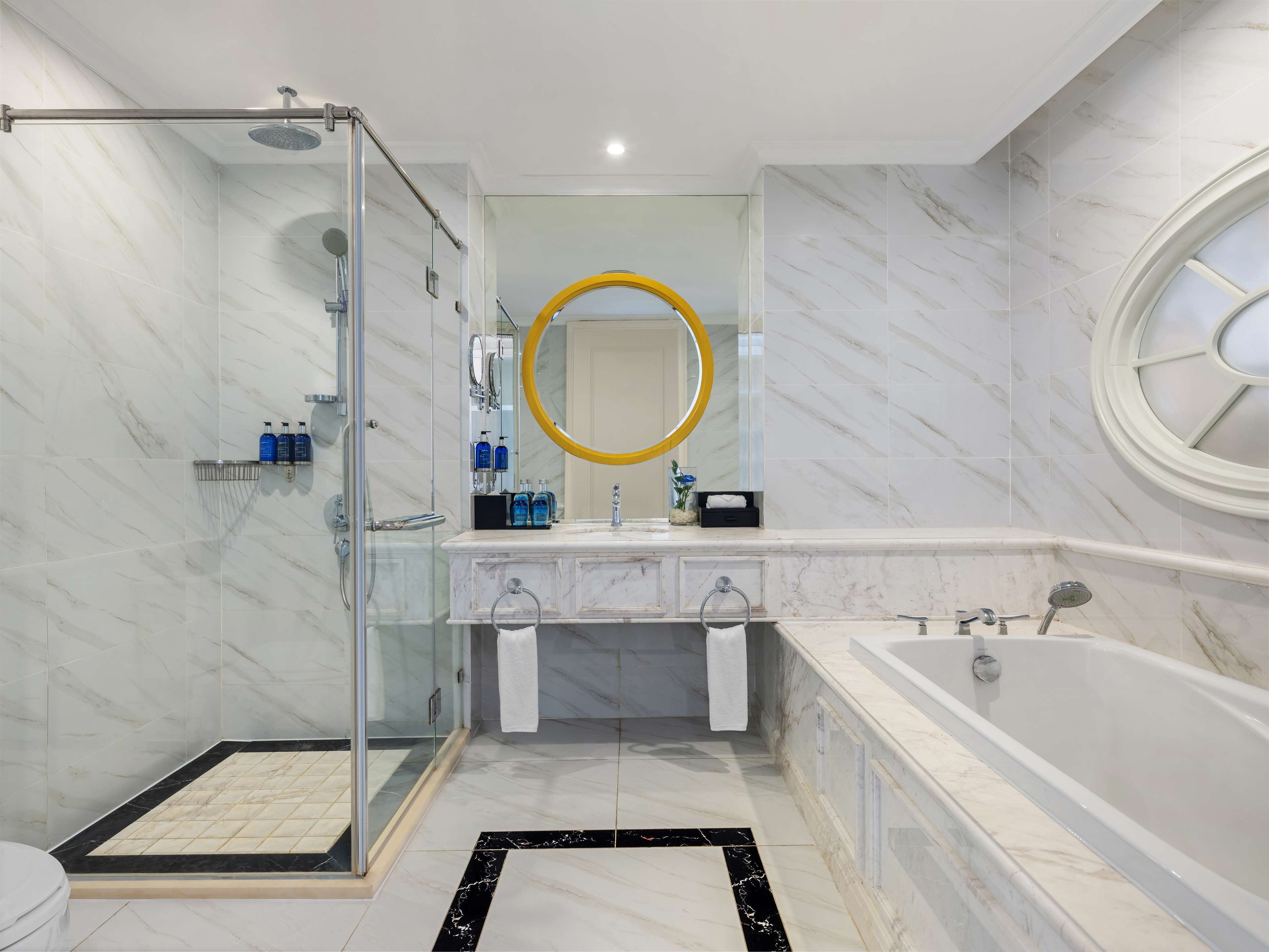 Un bagno moderno con doccia vetro, mobile lavabo con specchio e vasca da bagno.