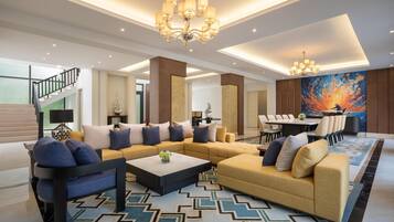 A modern living room with a sectional sofa, a coffee table, and a dining area with a large painting.