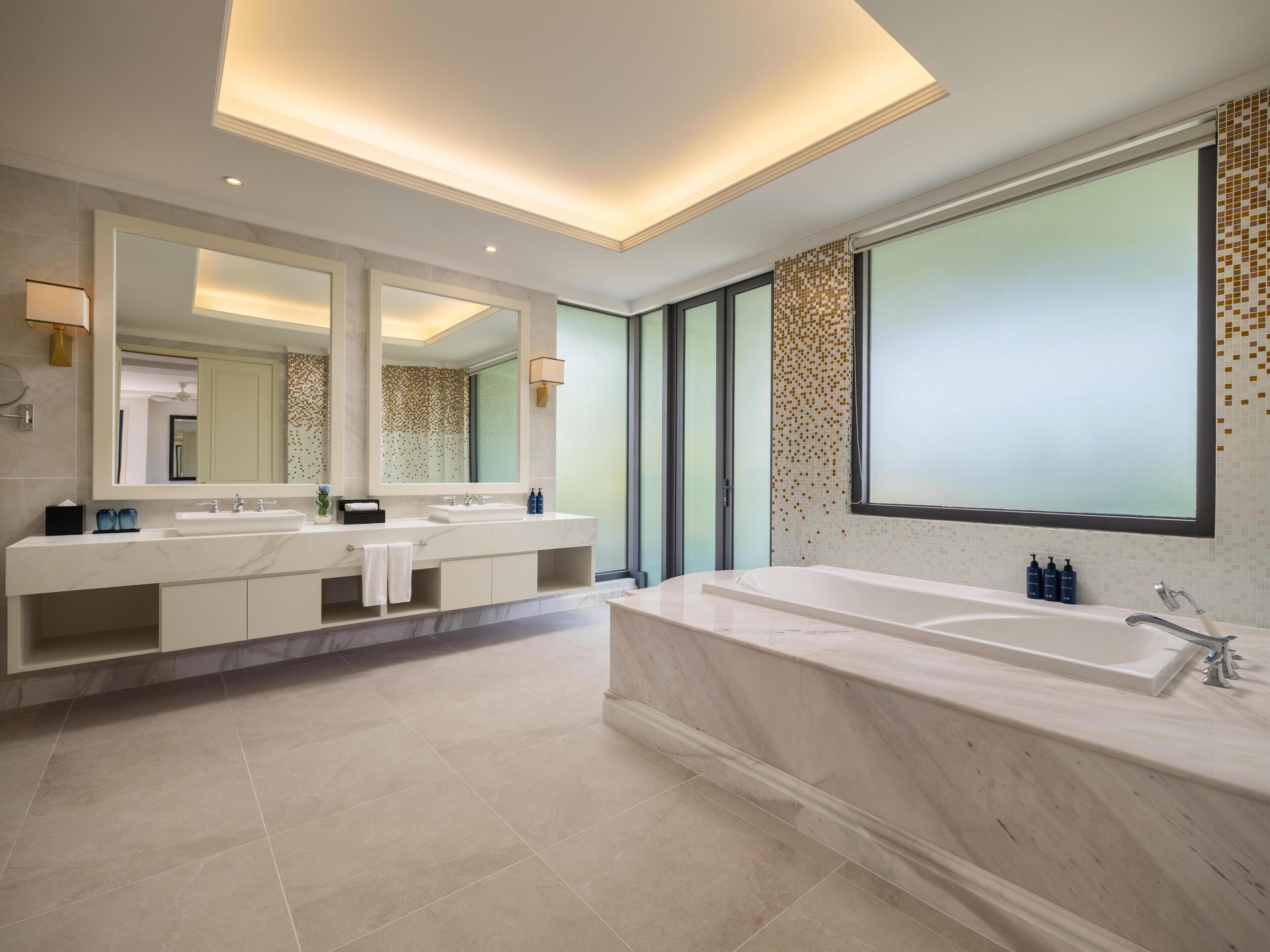 Une salle de bain moderne avec une grande baignoire, un meuble-lavabo à deux vasques et un grand miroir.