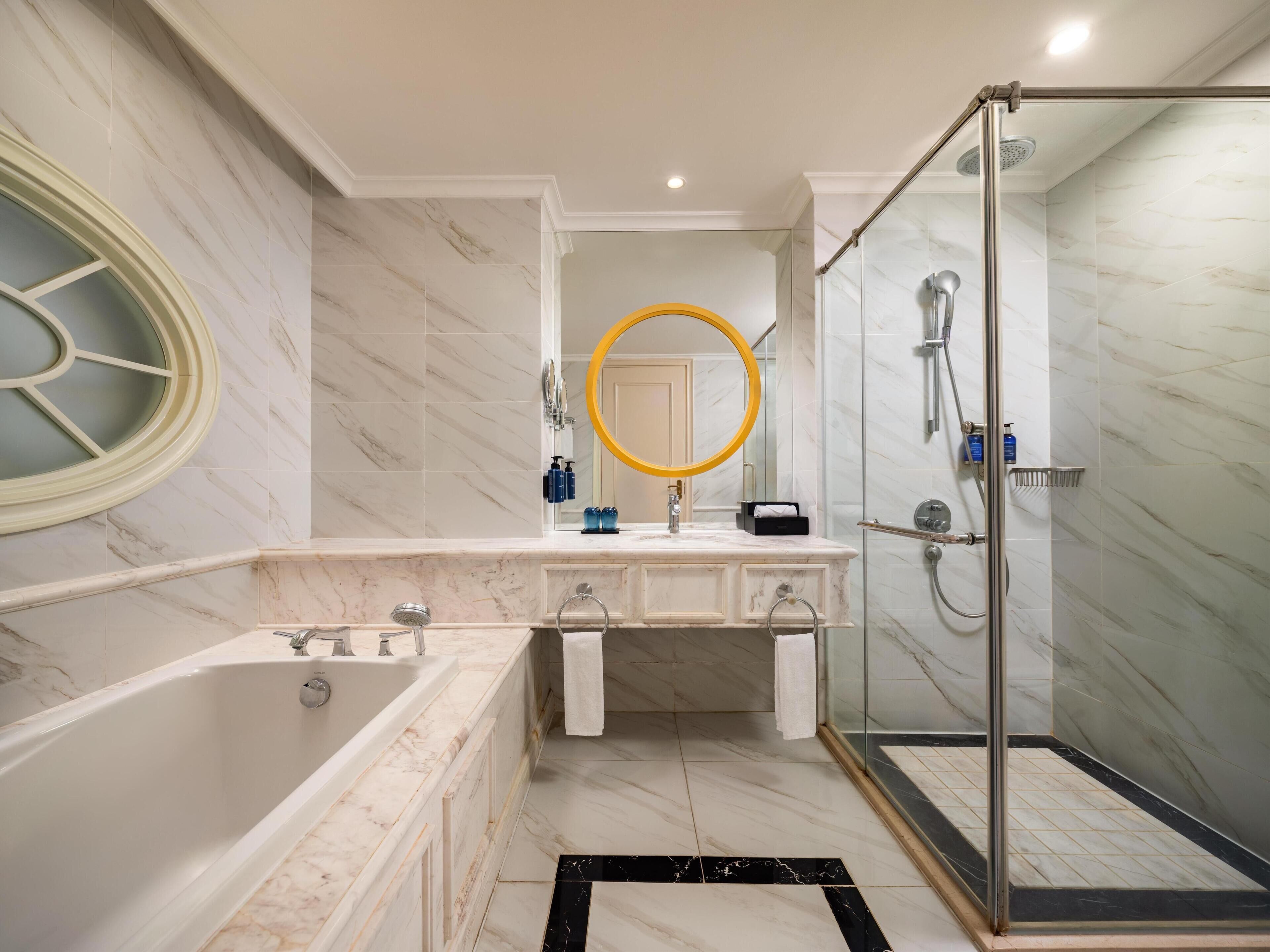 A modern bathroom with a bathtub, a glass-enclosed shower, and a vanity with a mirror.