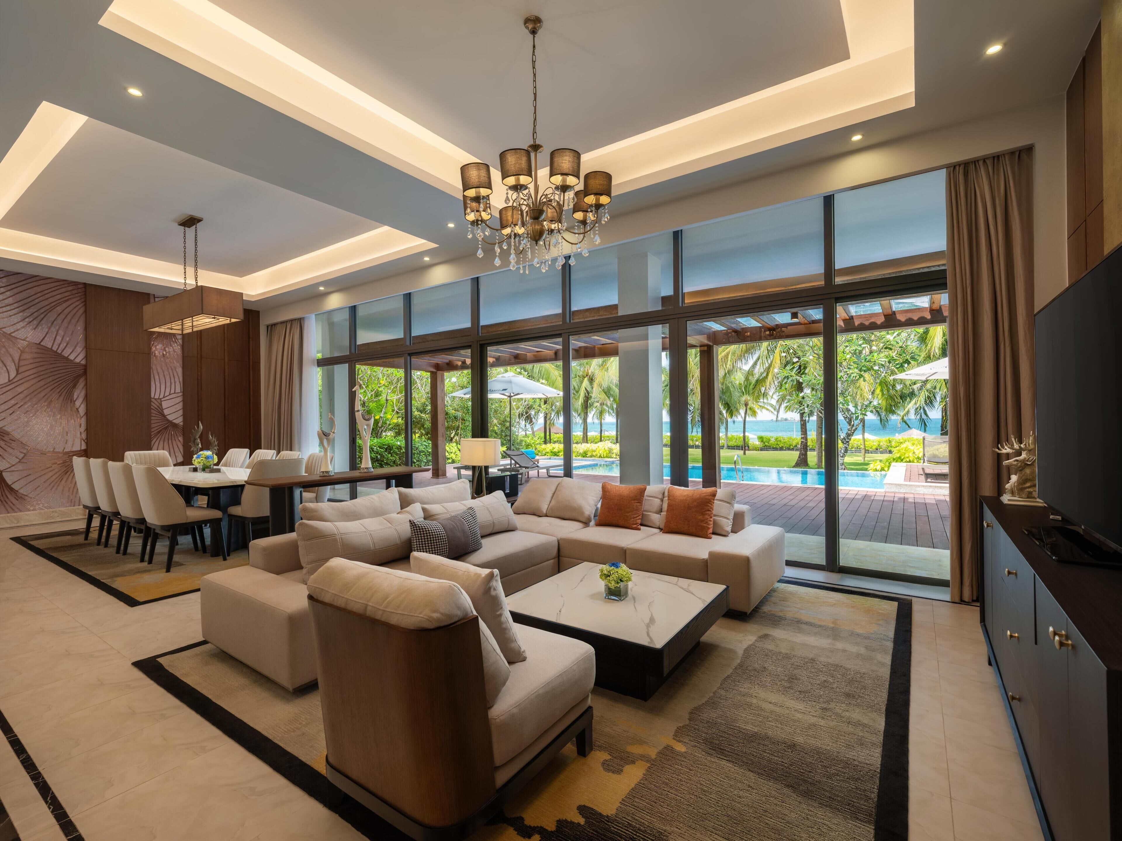 A modern living room with a large sofa, coffee table, and dining area.