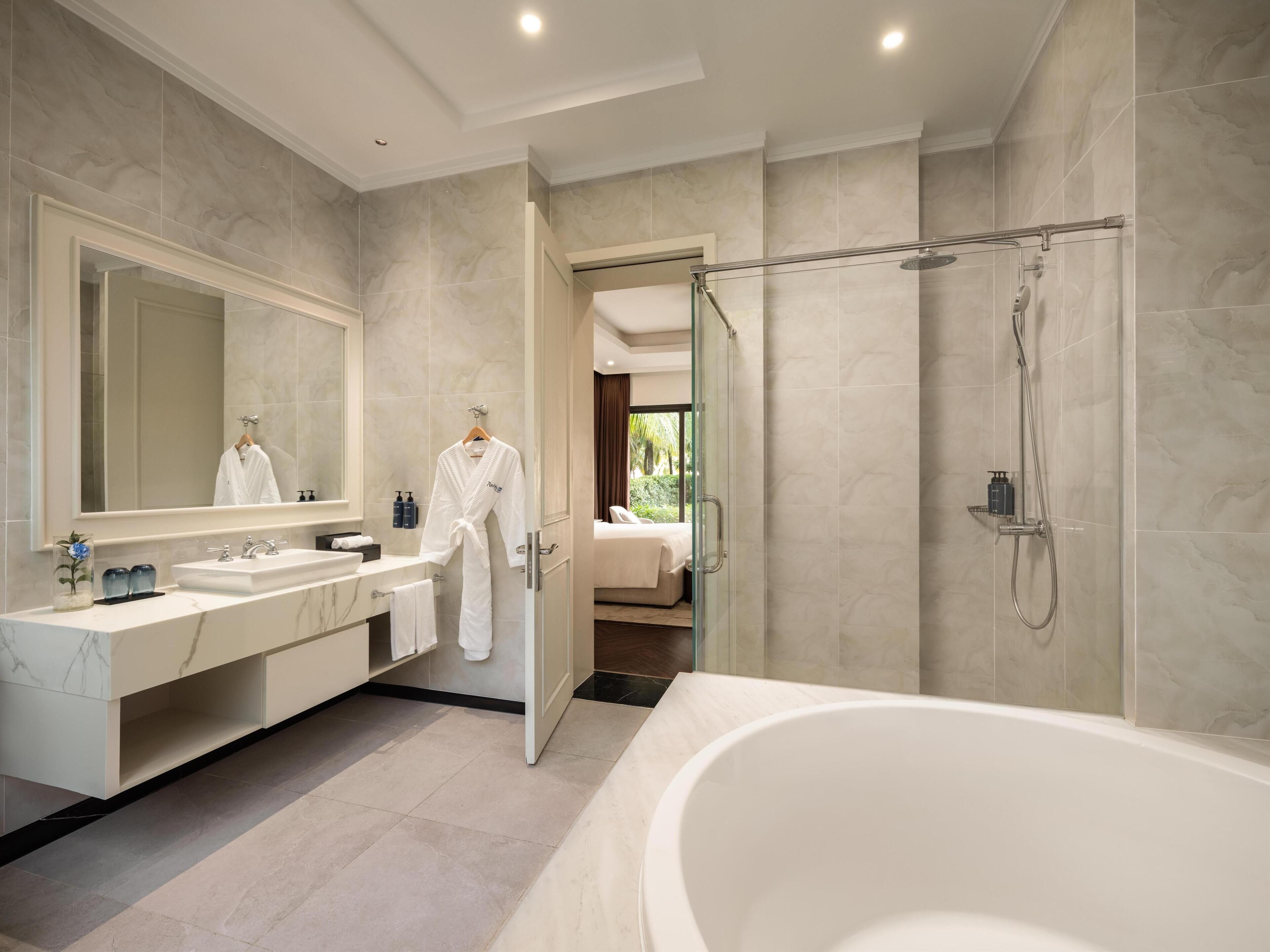 A modern bathroom with a large bathtub, a walk-in shower, and a vanity with a mirror.