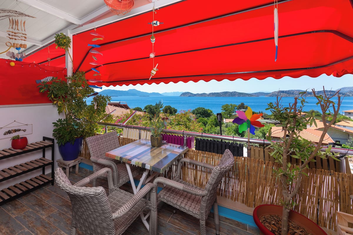 Een balkon met rieten meubels, een tafel en potplanten.