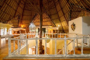 An interior with a thatched roof, wooden railings, and a staircase leading to an upper level. - Upani in Daini (Diani Beach)