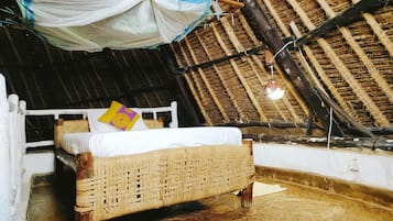 Cozy retreat with a single bed, woven headboard, and hanging mosquito net.