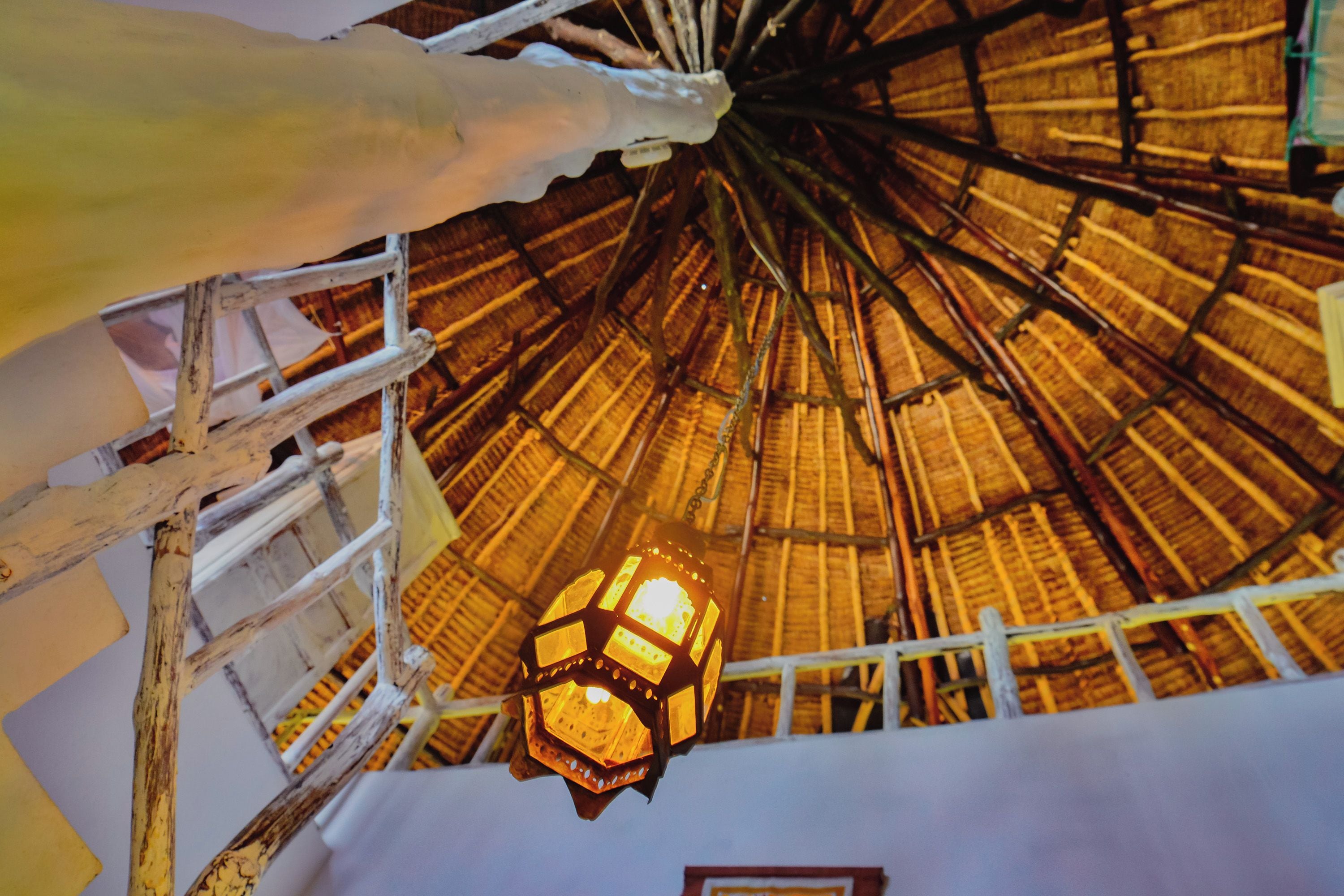 A thatched roof structure with a hanging light fixture.