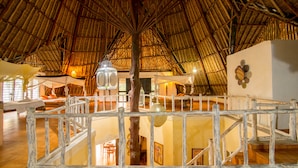 A spacious interior with a high thatched roof, wooden railings, and a central column. - Upani in Daini (Diani Beach)