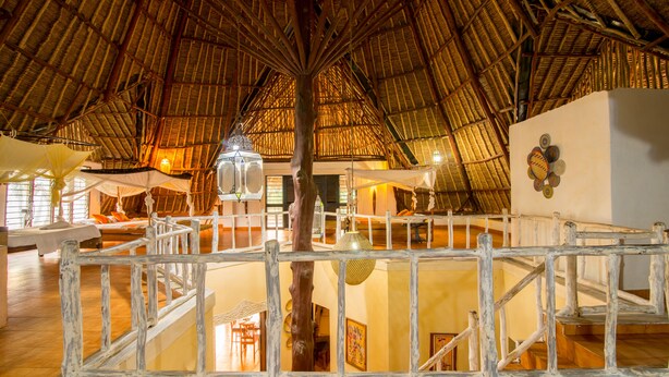 A spacious interior with a high thatched roof, wooden railings, and a central column. - Upani in Daini (Diani Beach)