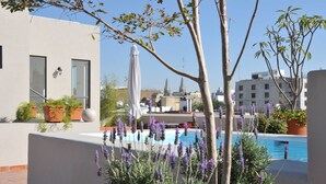 A rooftop pool area with a view of the cityscape, including buildings and a church spire. - Carlota (Guadalajara)