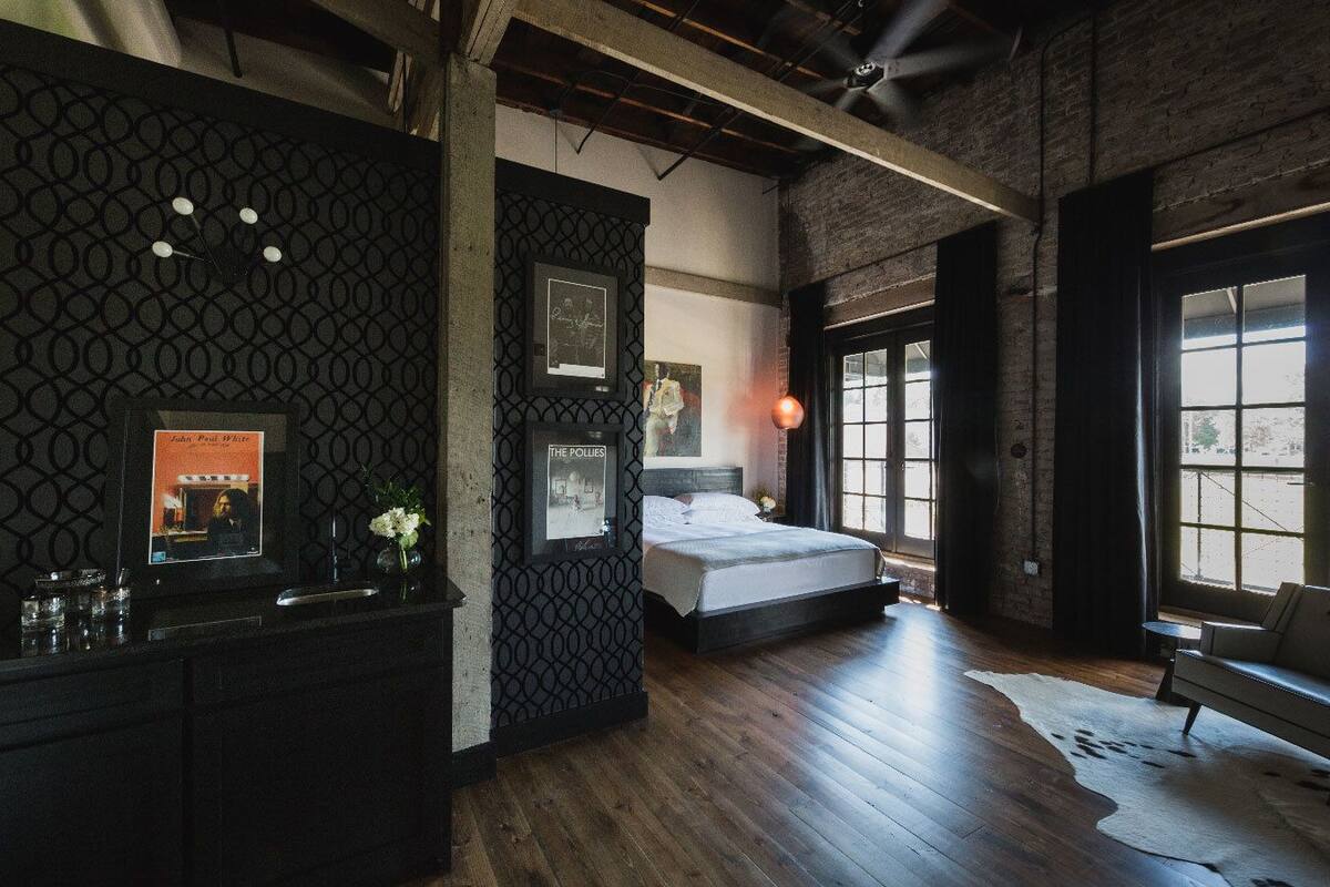 A modern bedroom with a large bed, a fireplace, and a view of the outdoors through a large window.