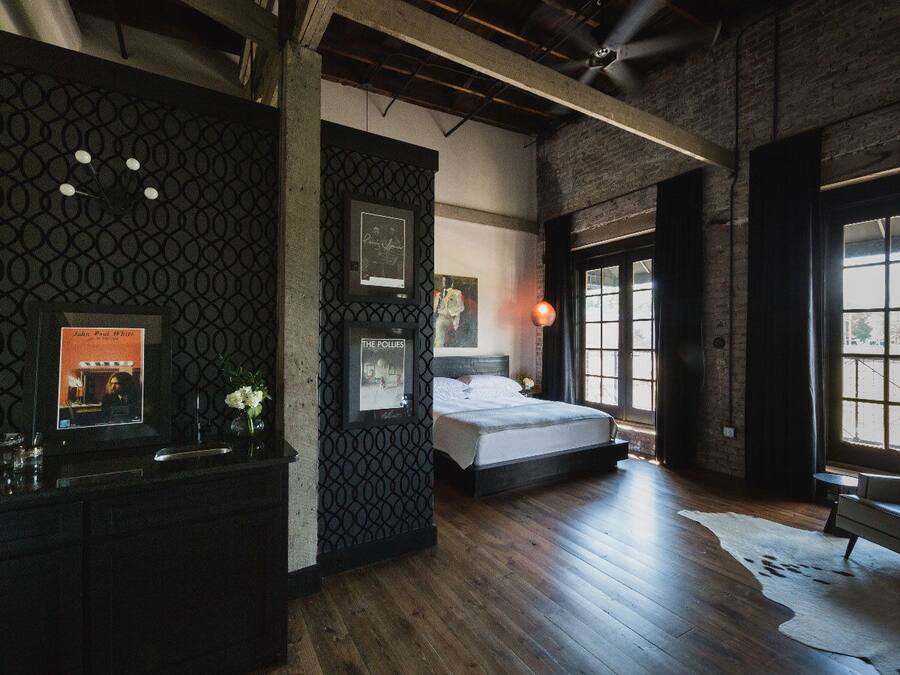 A modern bedroom with a large bed, a fireplace, and a view of the outdoors through a large window.