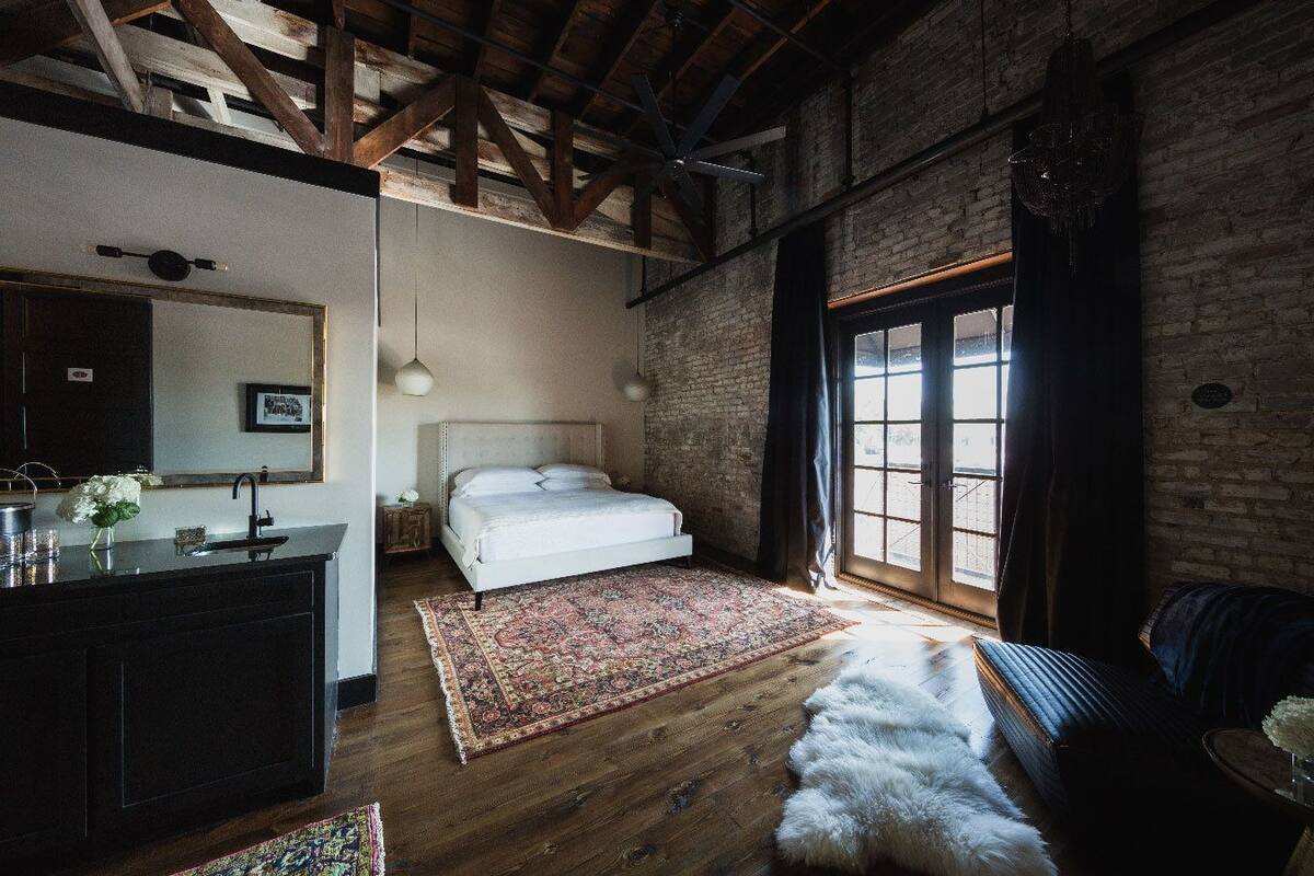 A bedroom with a bed, a dresser, a mirror, a window, and a door.