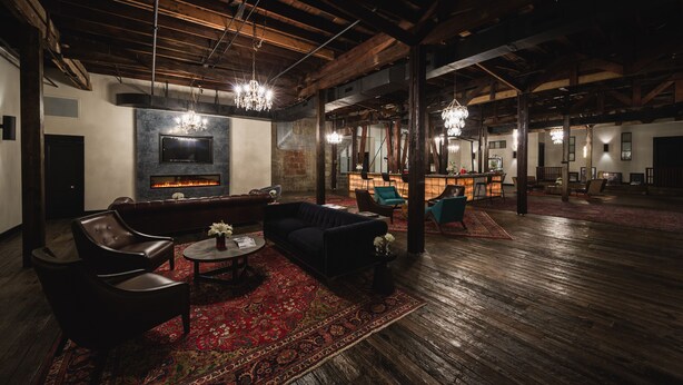 A spacious lounge with a fireplace, leather sofas, and a bar area. - GunRunner Boutique Hotel (Florence)