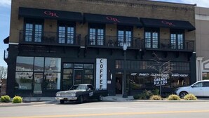A coffee shop with a large sign reading "COFFEE" and a smaller sign below stating "HOT SHAVES! CLEAN HANDS! ALWAYS FRESH!". - GunRunner Boutique Hotel (Florence)
