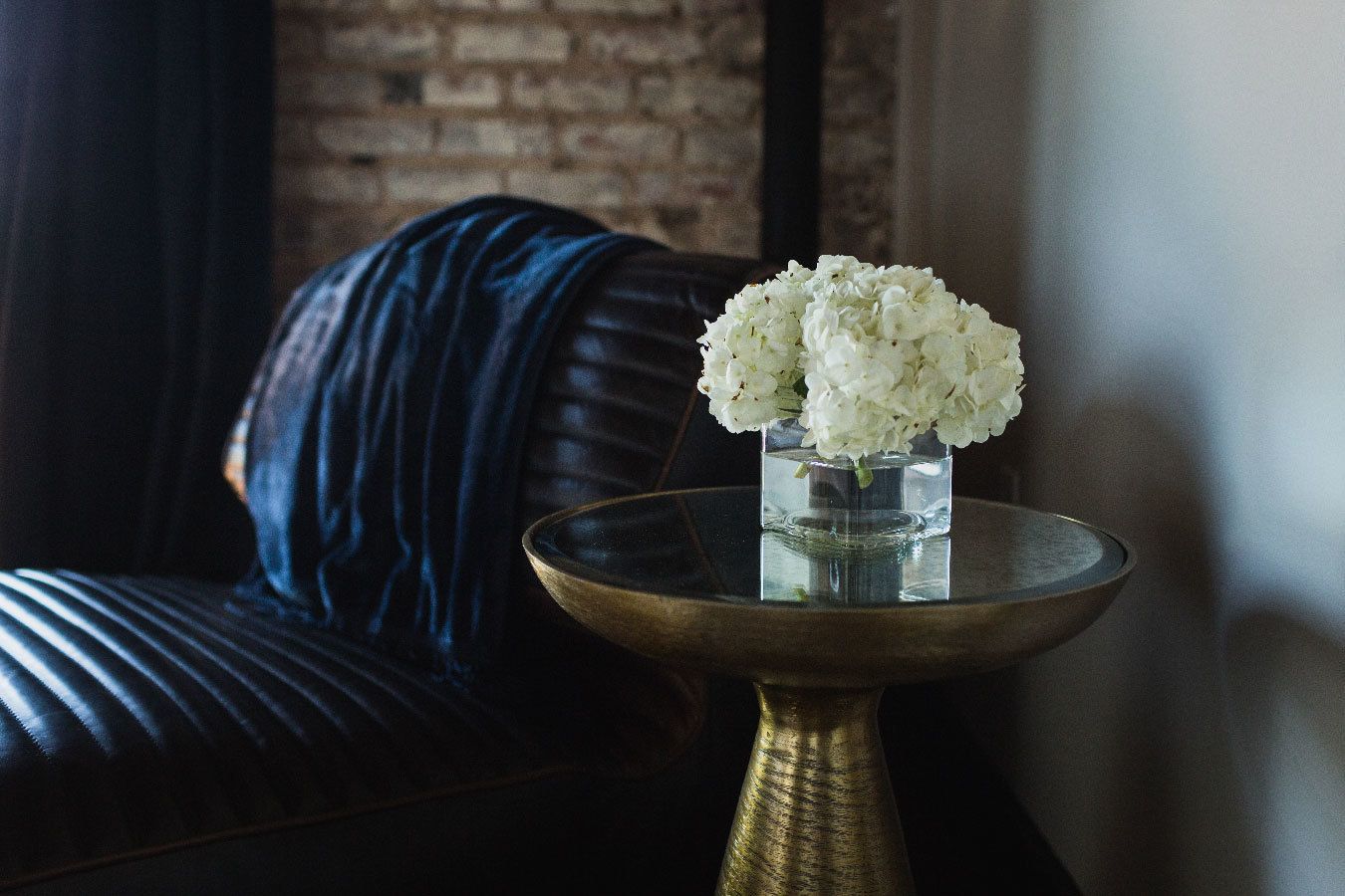 A glass vase with white flowers on a round table.