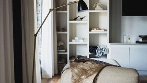 A bedroom with a bed, a floor lamp, a bookshelf, and a TV on the wall. - GunRunner Boutique Hotel (Florence)