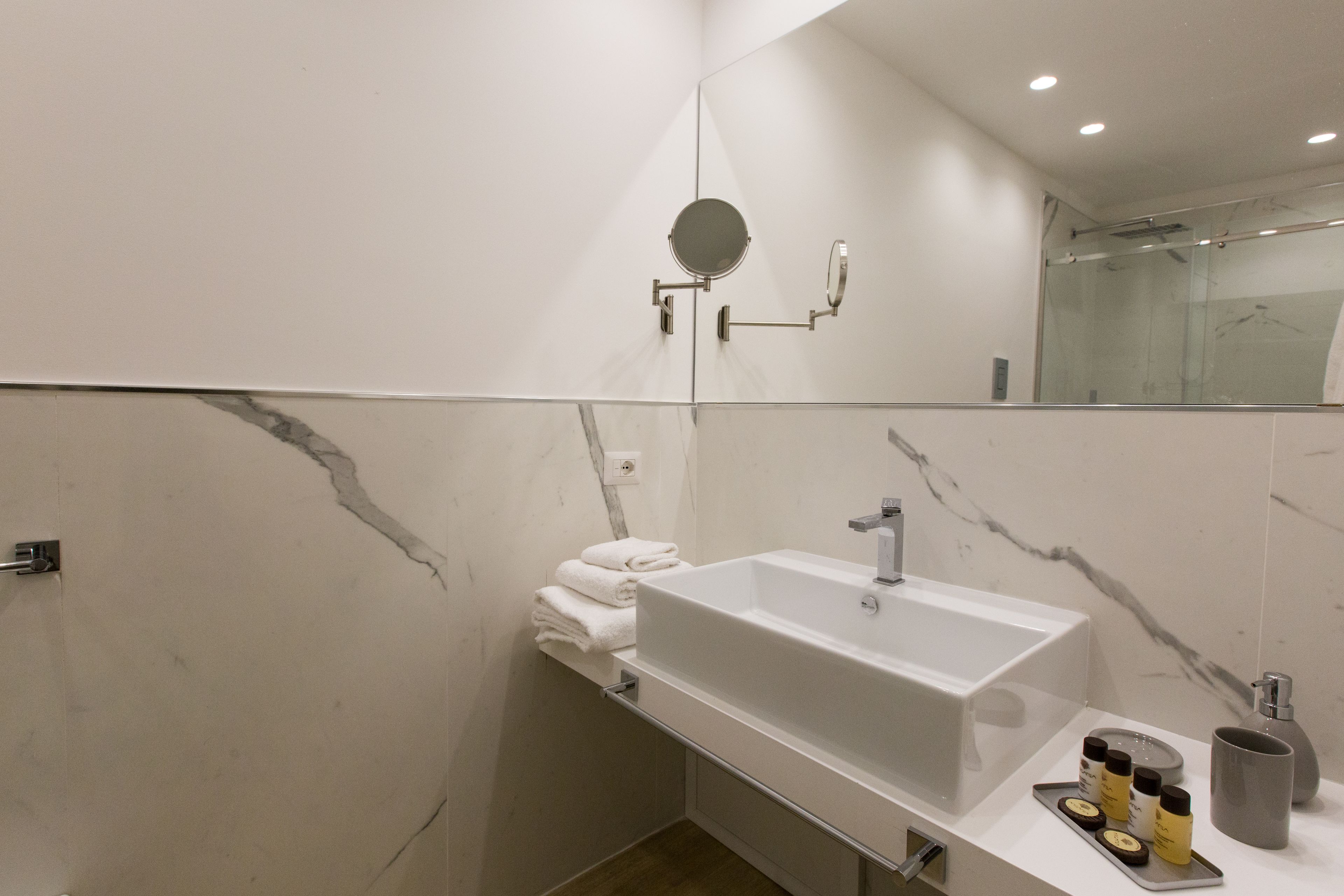 Ein modernes Badezimmer mit einem großen Waschbecken, einem Spiegel und einer Duschkabine aus Glas.