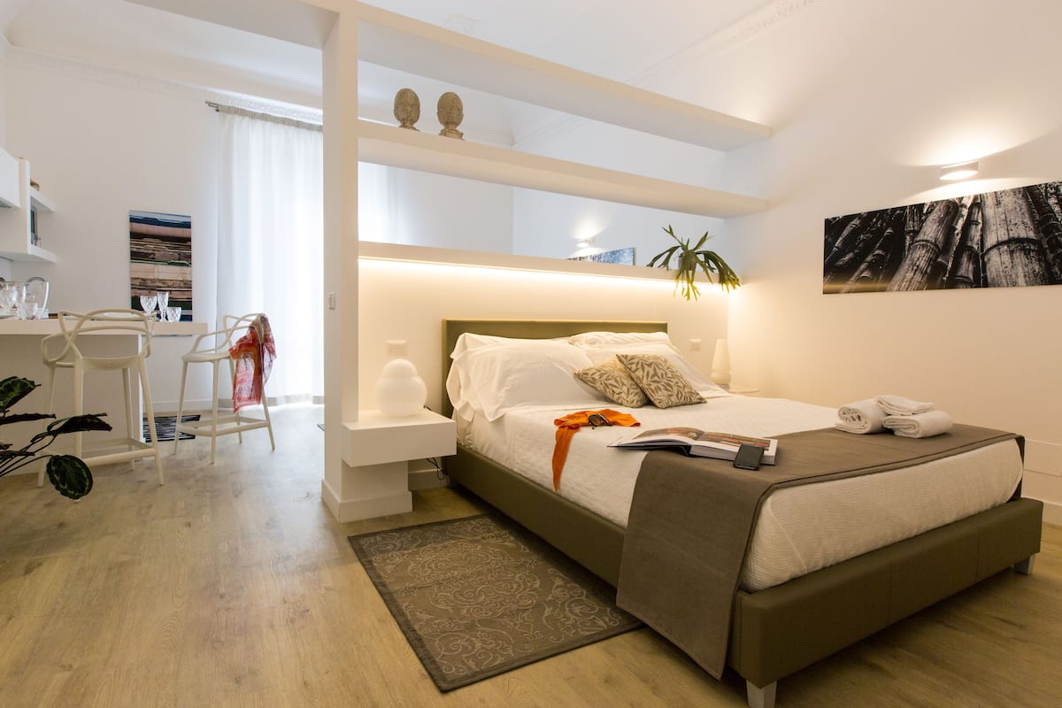 Ein modernes Schlafzimmer mit einem Bett, Nachttischen, einem Schreibtisch und einem Stuhl.