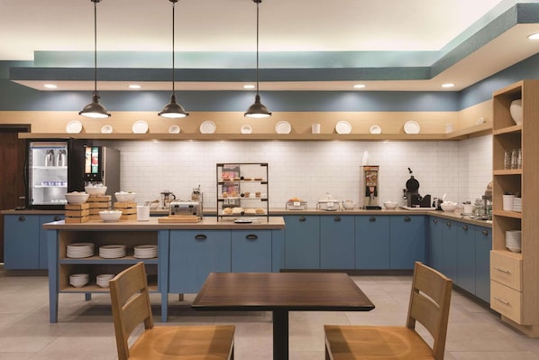 Una cocina moderna con armarios azules, una isla central e iluminación colgante.