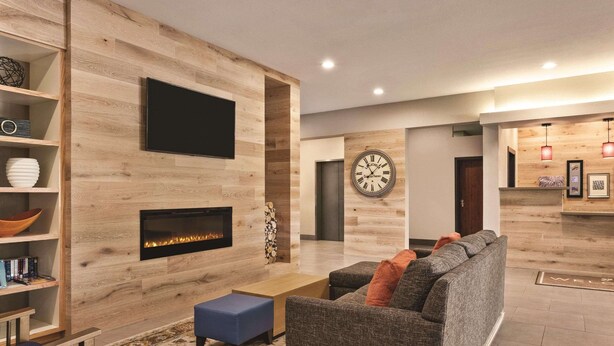 Una sala de estar moderna con chimenea, televisor y un reloj en la pared.