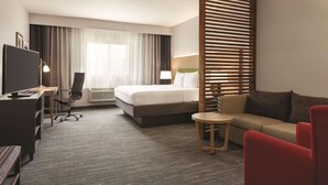 Habitación de hotel con cama, escritorio con computadora, televisor, sofá y una mesita.